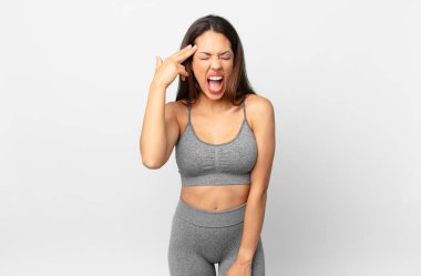 Genç İspanyol kadın mutsuz ve stresli görünüyor, intihar jesti silah işareti yapıyor. fitness konsepti