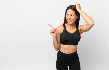 Genç İspanyol kadın şaşkın ve kafası karışık, kaşınan bir kafa hissediyor. fitness konsepti