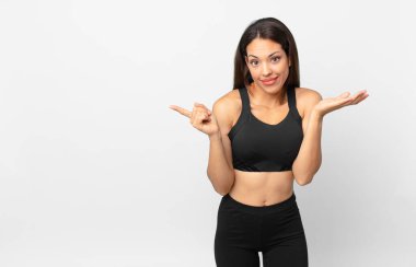 Genç İspanyol kadın şaşkın, şaşkın ve şüpheci hissediyor. fitness konsepti
