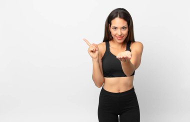 Genç İspanyol kadın mutlu bir şekilde gülümsüyor ve bir konsept sunuyor. fitness konsepti