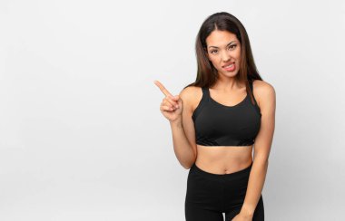 Genç İspanyol kadın şaşkın ve şaşkın görünüyor. fitness konsepti