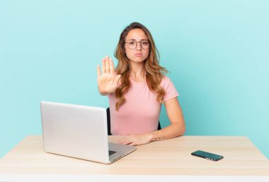 Güzel bir kadın ciddi görünüyor. Avuç içi gösteriyor. Durma hareketi yapıyor. telework konsepti