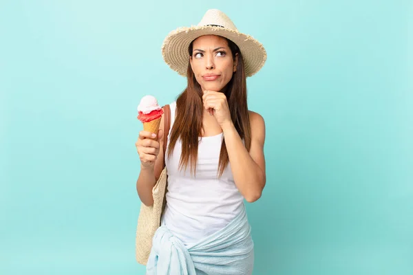 若いヒスパニック系の女性はアイスクリームを持っている疑いと混乱を感じて考えています 夏のコンセプト — ストック写真