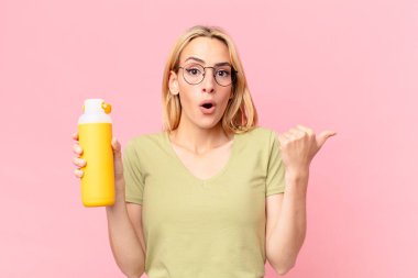 Sarışın, güzel bir kadın portakal suyu içiyor.