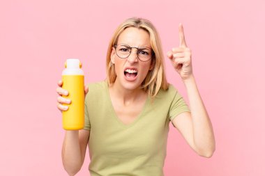 Sarışın, güzel bir kadın portakal suyu içiyor.