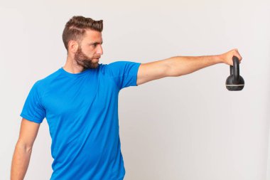 Genç fitness adamı dambılı kaldırıyor.