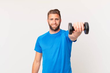 Genç fitness adamı dambılı kaldırıyor.