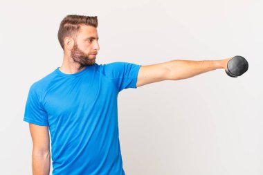 Genç fitness adamı dambılı kaldırıyor.