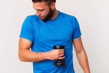 Genç fitness adamı dambılı kaldırıyor.