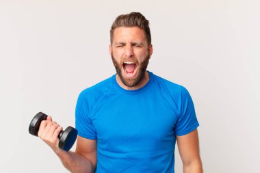 Genç fitness adamı dambılı kaldırıyor.