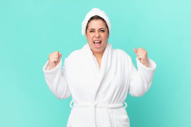 Duştan sonra bornoz giyen kıvrımlı, güzel bir kadın.