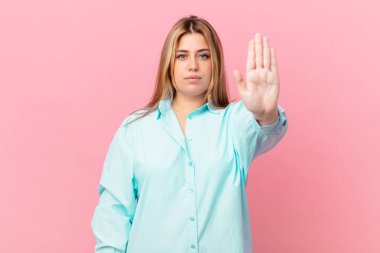 Kıvrımlı, güzel, sarışın kadın ciddi görünüyor.