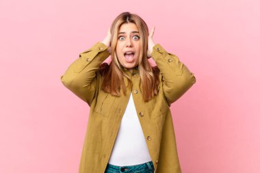 Kıvrımlı, güzel, sarışın kadın gergin, endişeli ya da korkmuş, elleri başının üstünde.