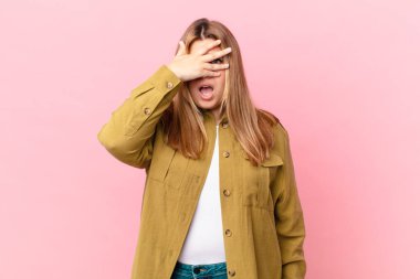 Kıvrımlı, güzel, sarışın kadın. Şok olmuş, korkmuş ya da korkmuş görünüyor.