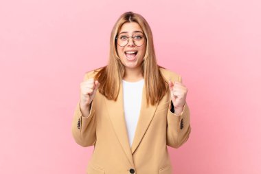 Kıvrımlı, güzel sarışın kadın şokta, gülüyor ve başarıyı kutluyor.