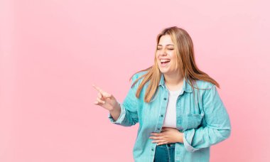 Kıvrımlı, güzel, sarışın kadın komik bir şakaya yüksek sesle gülüyor.