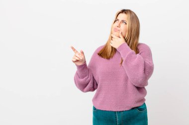 kıvrımlı, güzel sarışın kadın düşünüyor, kuşkulu ve şaşkın hissediyor.