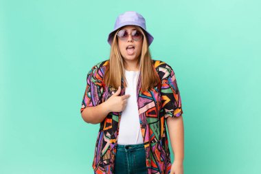 Kıvrımlı, güzel, sarışın kadın şok olmuş ve şaşırmış görünüyor. Ağzın sonuna kadar açık, kendini işaret ediyor.