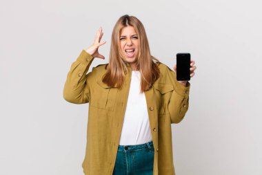 Eğri büğrü, güzel, sarışın kadın ellerini havaya kaldırıp bağırıyor ve akıllı bir telefon tutuyor.