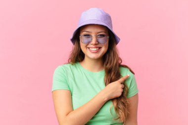 Genç, güzel bir kadın neşeyle gülümsüyor, mutlu hissediyor ve bir tarafı işaret ediyor. yaz konsepti