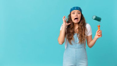 Genç ve güzel bir kadın ellerini havaya kaldırıp çığlık atıyor ve bir duvar boyuyor.