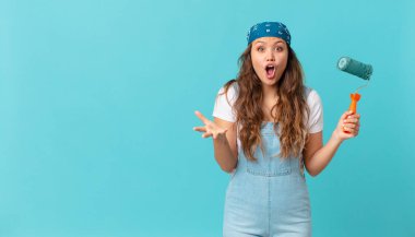 Genç, güzel bir kadın şok olmuş, şaşırmış ve duvar boyuyor.