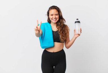 Gülümseyen ve mutlu görünen genç, güzel bir kadın zafer ya da huzur simgesi. fitness konsepti