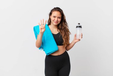 Genç, güzel bir bayan gülümsüyor ve arkadaş canlısı görünüyor, dört numarayı gösteriyor. fitness konsepti