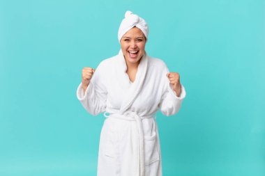 Genç, güzel bir kadın şoke olmuş, gülüyor, başarıyı kutluyor ve duş üstüne banyo bornozu giyiyor.