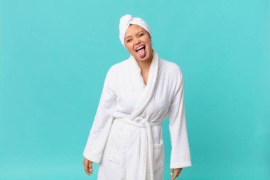 Neşeli ve asi tavırları olan genç ve güzel bir kadın, şaka yapıyor, dil çıkarıyor ve duştan sonra banyo cübbesi giyiyor.