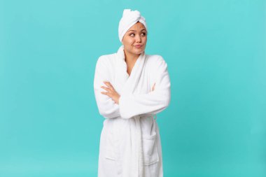 Genç, güzel bir kadın omuz silkiyor, kafası karışık ve kararsız ve duştan sonra banyo cübbesi giyiyor.