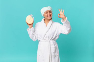 Genç, güzel bir kadın kendini mutlu hissediyor. Onayını gösteriyor. Güzel bir jest yapıyor ve duştan sonra bornoz giyiyor.