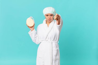 Genç, güzel bir kadın kendini kötü hissediyor, baş parmaklarını gösteriyor ve duştan sonra banyo cübbesi giyiyor.