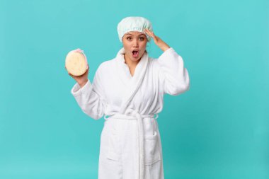 Genç, güzel bir kadın mutlu, şaşkın ve şaşırmış görünüyor ve duştan sonra banyo cübbesi giyiyor.