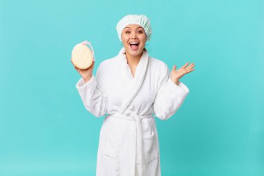 Genç ve güzel bir kadın inanılmaz bir şey karşısında şaşkın ve mutlu hissediyor ve duştan sonra banyo cübbesi giyiyor.