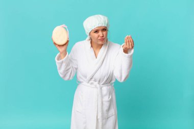 Genç ve güzel bir kadın kapiş ya da para jesti yapıyor, sana ödemeni söylüyor ve duştan sonra banyo cüppesi giyiyor.