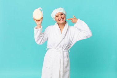 Genç, güzel bir kadın, kendine güvenerek gülümsüyor. Duştan sonra banyo cübbesi giyiyor.