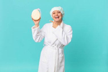 Genç ve güzel bir kadın heyecanlı ve şaşırmış görünüyor. Yan tarafı gösteriyor ve duştan sonra banyo cübbesi giyiyor.