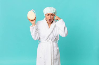 Genç, güzel bir kadın şaşırmış görünüyor, yeni bir düşünce, fikir ya da konsept fark ediyor ve duştan sonra banyo bornozu giyiyor.