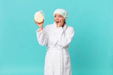 Genç ve güzel bir kadın mutlu, heyecanlı ve şaşırmış hissediyor ve duştan sonra banyo cübbesi giyiyor.