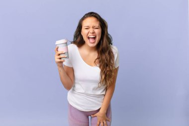 Genç ve güzel bir kadın agresif bir şekilde bağırıyor, kızgın görünüyor ve elinde kahve tutuyor.