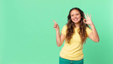 Genç, güzel bir kadın kendini mutlu hissediyor. Onayını veriyor. Güzel bir jest yapıyor ve fotokopi alanını işaret ediyor.