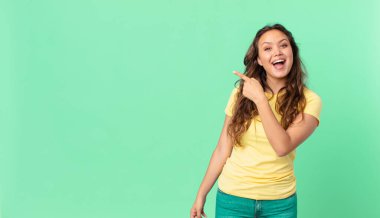 Genç ve güzel bir kadın heyecanlı ve şaşırmış görünüyor. Yan tarafı gösteriyor ve fotokopi alanını işaret ediyor.