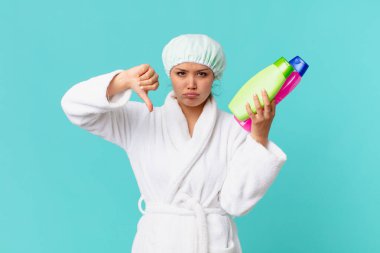 Bornoz giyen ve elinde temiz bir ürün şişesi tutan genç ve güzel bir kadın.