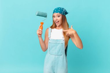 Güzel bir kadın kendini mutlu hissediyor ve heyecan dolu bir resimle kendini işaret ediyor. Yeni bir ev duvarı.