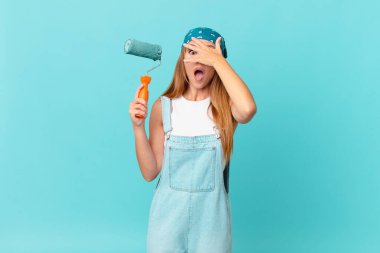 Güzel bir kadın şok olmuş, korkmuş ya da korkmuş görünüyor. Yüzü elle kaplanmış yeni bir ev duvarı boyuyor.