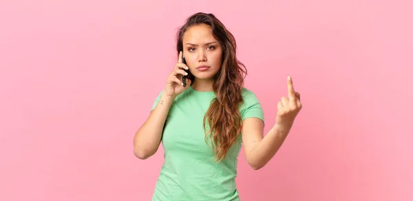 若い女性は怒り いらいらし 反抗的で攻撃的でスマートフォンを持っています — ストック写真
