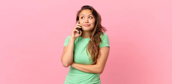 Jovem Mulher Bonita Encolhendo Ombros Sentindo Confuso Incerto Segurando Telefone — Fotografia de Stock