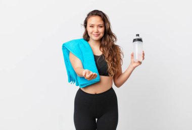 Genç ve güzel bir kadın arkadaşça gülümsüyor ve bir konsept sunuyor. fitness konsepti