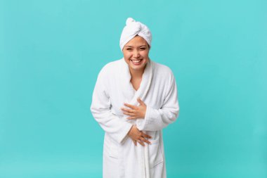Genç ve güzel bir kadın komik bir şakaya yüksek sesle gülüyor ve duştan sonra banyo cübbesi giyiyor.